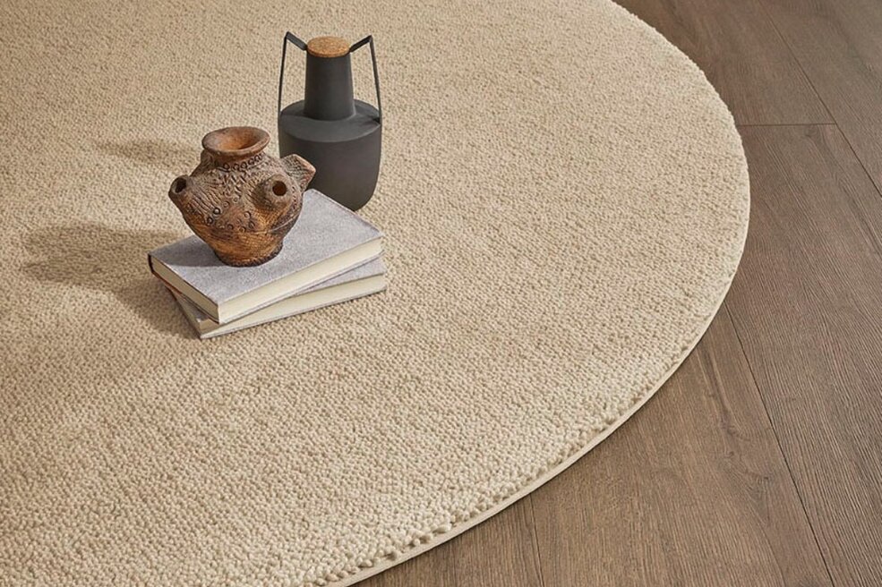 Runder, abgepasster JOKA Teppichboden Wool Vida als textile Insel auf Holzboden.