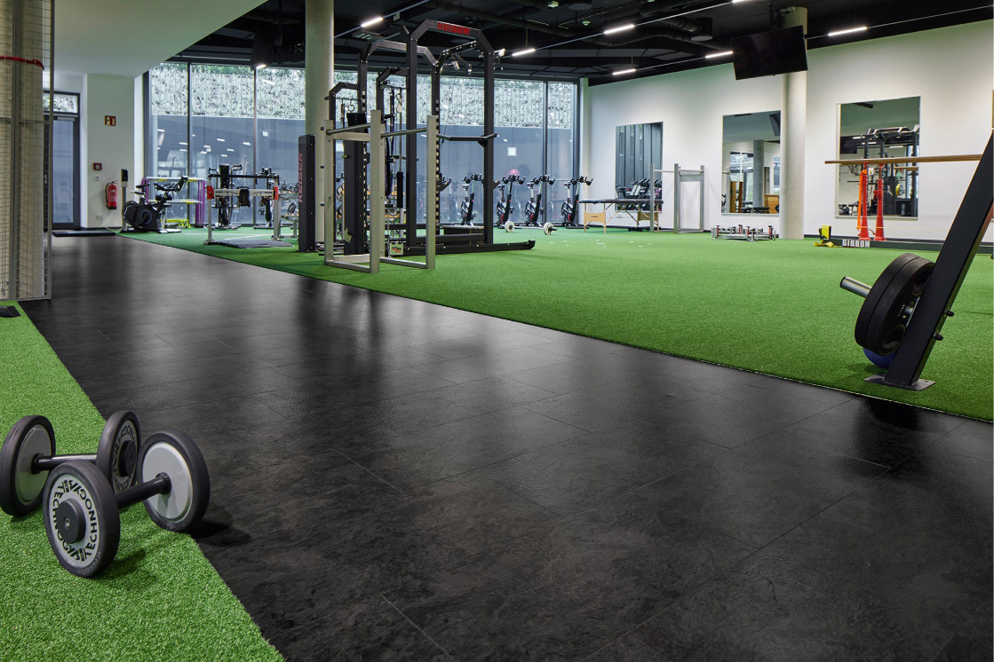 JOKA-Referenzen-Designboden-Eintracht-Frankfurt-Fitnesstudio Raumbild eines Eintracht Frankfurt Fitnessstudios, in dem ein sehr dunkler JOKA Designboden 555 verlegt ist.