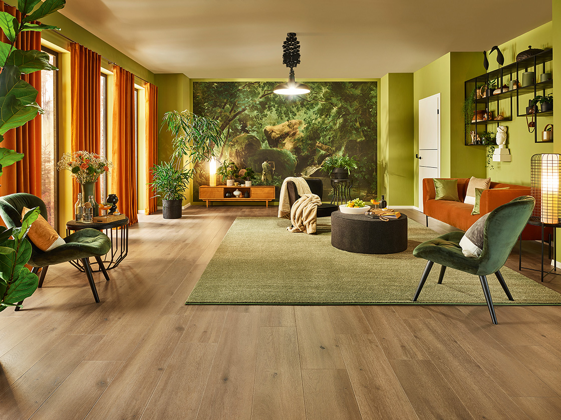 JOKA-Raumbild-Fußboden-Xplora-NEXT-Wald Raumbild eines Wohnzimmers mit vielen Zimmerpflanzen, in dem ein dunkler JOKA Xplora NEXT Naturdesignboden verlegt ist.