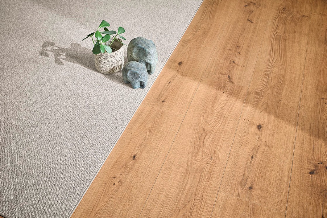 Detailansicht des abgepassten JOKA Teppichboden Wool Denia, kombiniert mit angrenzendem Holzboden.